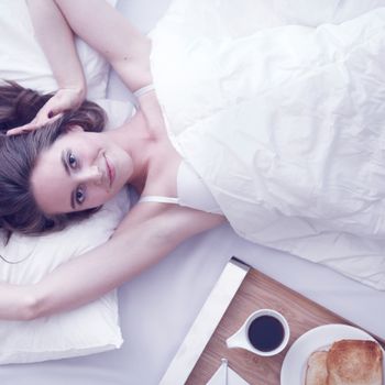 Beautiful young woman having breakfast in bed