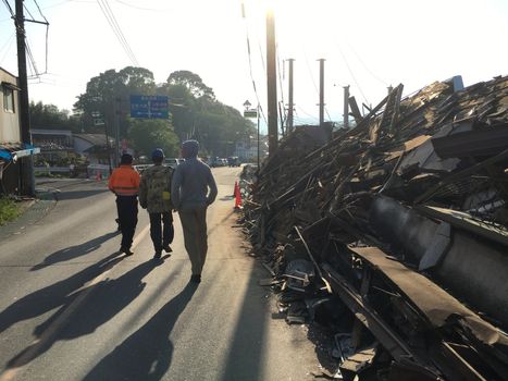 JAPAN, Mashiki: Men walk along the rubble of collapsed houses following an earthquake, on April 20, 2016 in Mashiki near Kumamoto, Japan. As of April 20, 48 people were confirmed dead after strong earthquakes rocked Kyushu Island of Japan. Nearly 11,000 people are reportedly evacuated after the tremors Thursday night at magnitude 6.5 and early Saturday morning at 7.3.