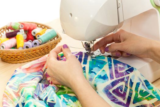 hands of the seamstress sew on the sewing machine on a table