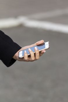 the girl in the arm with a French manicure keeps mobile phone