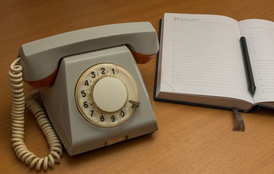 The photo depicts a landline phone with a notebook