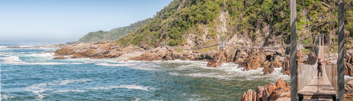 STORMS RIVER MOUTH, SOUTH AFRICA - FEBRUARY 29, 2016:  Unidentified tourists on the suspension bridge over the mouth of the Storms River. The restaurant is visible to the far left