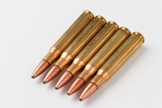 Five .30-06 caliber hunting rifle cartridges in a row on a white background