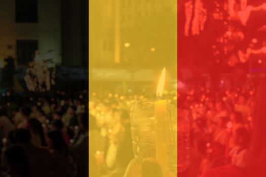 Belgium flag and people praying in background.