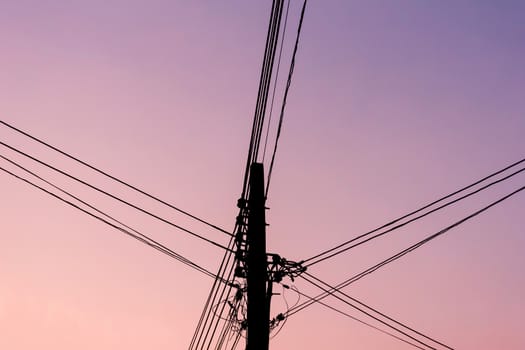 Silhouette electric pole in evening with twilight sky.