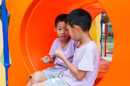 Twin Thai boy playing rock-paper-scissors at playground.