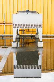 Air conditioner fan reflect in water with yellow wall.