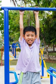 Thai boy hanging bar at playground.