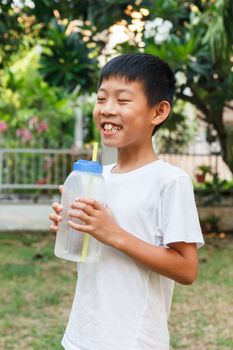 Thai boy drink cold water from plasctic bottle using straw.