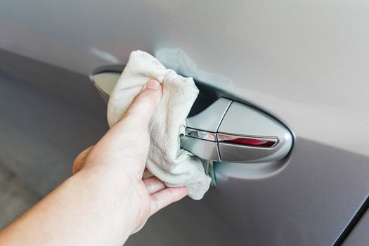 Hand cleaning car handle with chamois towel.