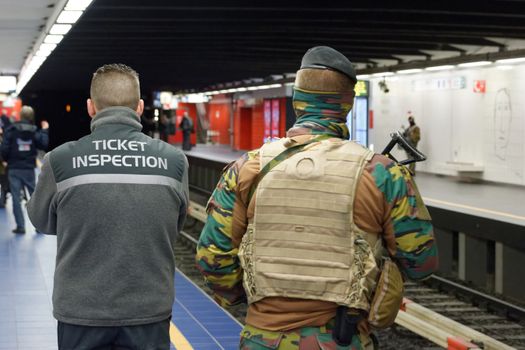BELGIUM, Brussels : A Belgian serviceman stands guard as a train arrives at the Maelbeek - Maalbeek metro station on its re-opening day on April 25, 2016 in Brussels, after being closed since the 22 March attacks in the Belgian capital.Maelbeek - Maalbeek metro station was hit by one of the three Islamic State suicide bombers who struck Brussels airport and metro on March 22, killing 32 people and injuring hundreds. 