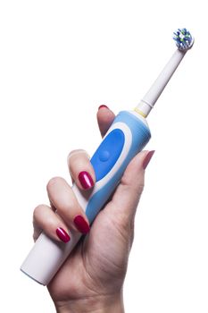 Hand with manicure holds single blue electric toothbrush against white background