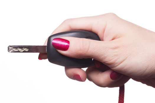 Close up of manicured hand with red nail polish holding black car key on white background