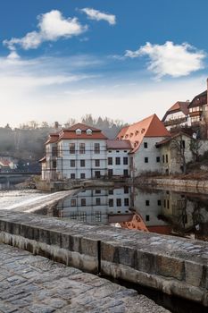 General Cesky Krumlov view with historical small houses along the river, on cloudy blue sky background.