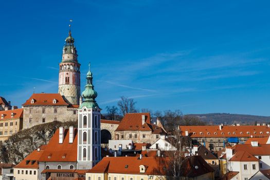 General Cesky Krumlov view with gothic towers and historical small houses around,  on bright sky background.