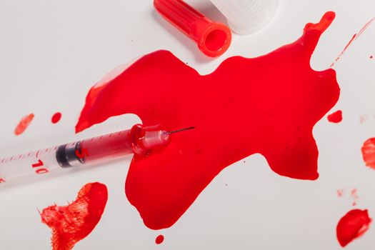 High Angle View of Syringe Needle Squirting Red Liquid or Blood onto White Background in Studio Still Life - Concept Image