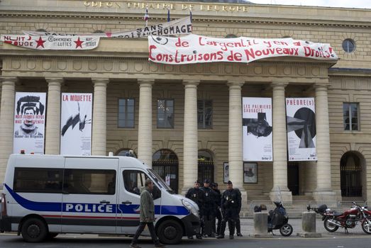 FRANCE, Paris : Policemen stand guard outside the Odeon theatre as French artists and entertainment workers known in France as intermittents du spectacle occupy the building and display a banner reading There is money, let's build new rights in Paris on April 25, 2016.Around 50 people occupied the building to protest against the French government's proposed labour reforms and to demand the reshaping of the unemployment insurance before the start of the unemployment insurance negotiations, as part of a protest in conjunction with the Nuit Debout (Night Rising) movement against the French government's proposed labour reforms. 