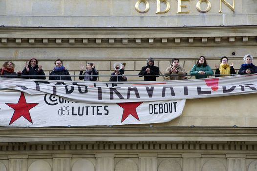 FRANCE, Paris : Men stand by banners reading fights' convergence displayed on the top of the Odeon theatre as French artists and entertainment workers known in France as intermittents du spectacle occupy the building in Paris on April 25, 2016.Around 50 people occupies the building to protest against the French government's proposed labour reforms and to demand the reshaping of the unemployment insurance before the start of the unemployment insurance negotiations, as part of a protest in conjunction with the Nuit Debout (Night Rising) movement against the French government's proposed labour reforms. 