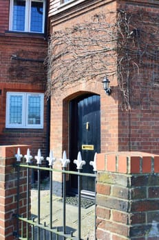 Black doorway with brick and metal fence