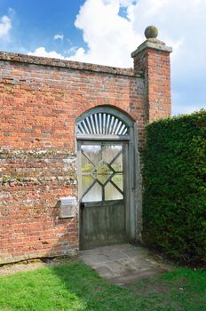 Wooden garden gate with red brick wall