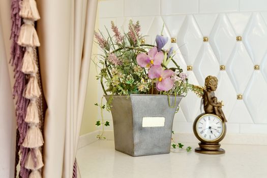 flowers in a pot and the watch has come to a standstill on a table about a window with curtains