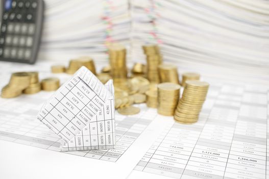 Bankruptcy of house with step pile of gold coins fall to the ground on finance account have blur calculator and pile of document as background.