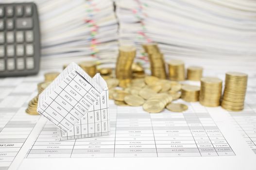 Bankruptcy of house with step pile of golden coins fall to the ground on finance account have blur pile of document with calculator as background.