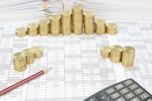 Brown pencil on finance account have step pile of gold coins with calculator and pile of document as background.