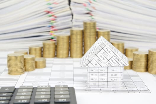 House on finance account have blur calculator and step pile of gold coins with pile of document as foreground and background.