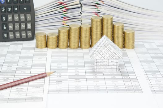 House with pencil on finance account have blur step pile of gold coins and pile of document with calculator as background.