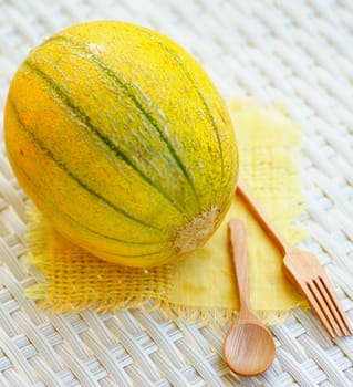 Fresh Ripe Melon Full Body  with Wooden Fork and Spoon closeup on White Wicker background