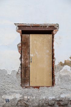 Close up detailed view of old wooden door on a white wall.