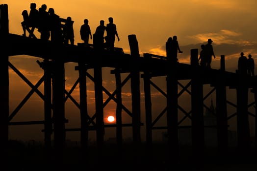 Silhouetted people crossing U bein bridge with sunset,The longest wooden bridge in Mandalay,Myanmar.