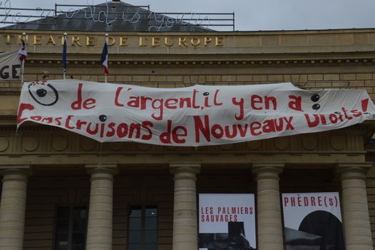 FRANCE, Paris : A man stands by banners reading There is money, let's build new rights displayed on the top of the Odeon theatre as French artists and entertainment workers known in France as intermittents du spectacle occupy the building in Paris on April 25, 2016. Around 50 people occupies the building to protest against the French government's proposed labour reforms and to demand the reshaping of the unemployment insurance before the start of the unemployment insurance negotiations, as part of a protest in conjunction with the Nuit Debout (Night Rising) movement against the French government's proposed labour reforms.