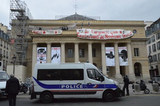 FRANCE, Paris : Policemen stand guard outside the Odeon theatre as French artists and entertainment workers known in France as intermittents du spectacle occupy the building and display a banner reading There is money, let's build new rights in Paris on April 25, 2016. Around 50 people occupied the building to protest against the French government's proposed labour reforms and to demand the reshaping of the unemployment insurance before the start of the unemployment insurance negotiations, as part of a protest in conjunction with the Nuit Debout (Night Rising) movement against the French government's proposed labour reforms. 