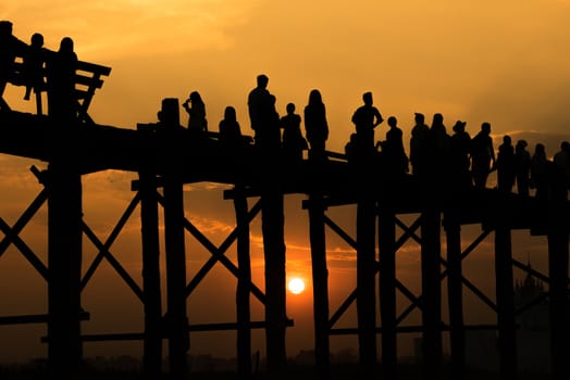 Silhouetted people crossing U bein bridge with sunset,The longest wooden bridge in Mandalay,Myanmar.