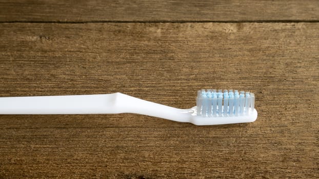 The clean white toothbrush on old wooden planks for brushing the teeth.