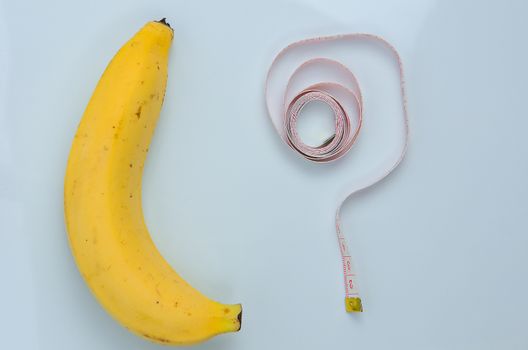 Large banana with measuring tape on white background