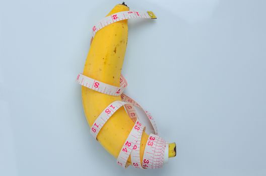 Large banana with measuring tape on white background