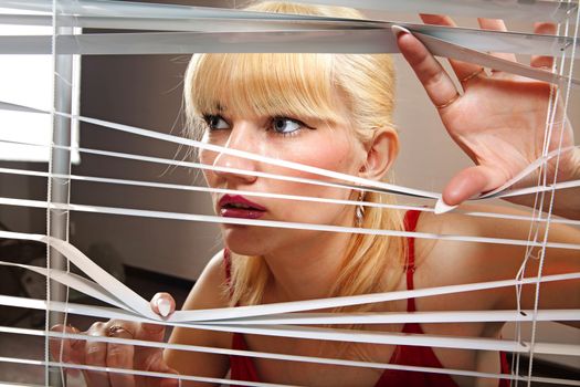 look of blonde woman who observes through blinds