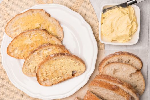 Fresh bread and homemade butter on wooden background. Top view with copy space.