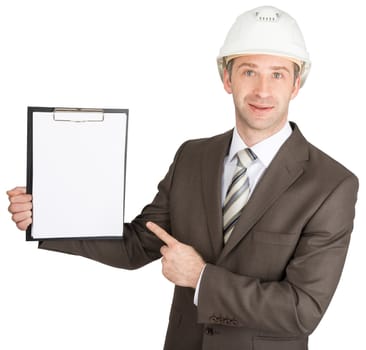 Businessman in suit and helmet pointing on clipboard, smiling at camera. White background