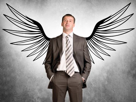 Businessman with drawn angel wings looking at camera on grey background