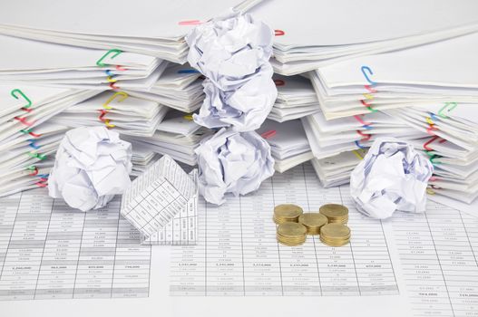 Bankruptcy of house with pile of gold coins as cross on finance account have blur paper ball and pile of paperwork with colorful paperclip as background.