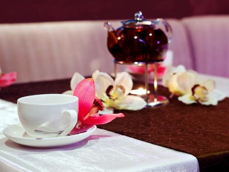 Cup and teapot of tea on table with flowers