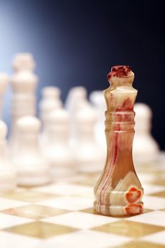 Set of chess pieces made from Onyx on board against dark background