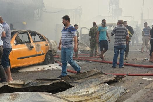 IRAQ, Baghdad: People gather in a predominantly Shi'ite Muslim district of eastern Baghdad as Iraqi security forces and firefighters secure the site of a suicide bombing claimed by the Islamic State group in New Baghdad area, on April 25, 2016. The blast ripped through shops, killing at least eleven people.