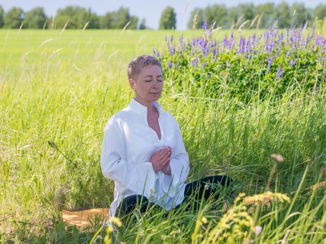 Mature woman practices yoga in nature