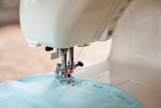 Sewing process. Sewing machine with twin needle and blue fabric