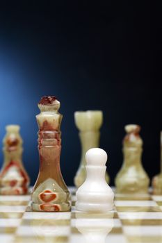 Set of chess pieces made from Onyx on board against dark background